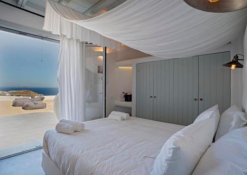 a bedroom with a white bed with a view of the ocean at Villa Maera 2 in Kalo Livadi