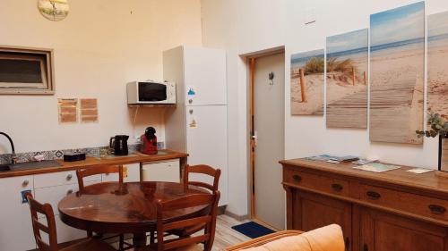 a kitchen with a table and a small table and a refrigerator at Logis des Lauriers Roses in Marennes