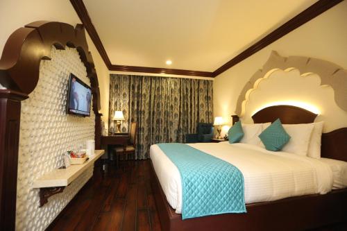 a hotel room with a large bed and a television at Comfort Inn Sapphire - A Inde Hotel in Jaipur