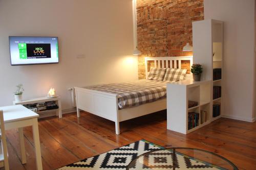 sypialnia z łóżkiem i telewizorem na ścianie w obiekcie Apartament z patio w centrum Starego Miasta w Toruniu