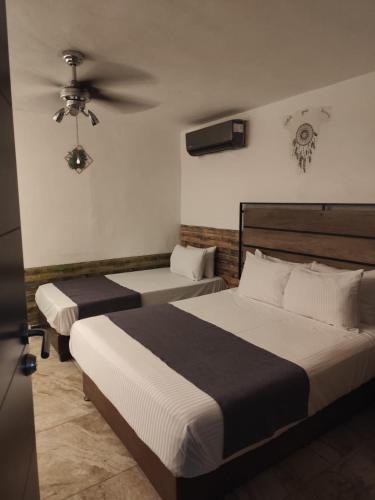 a bedroom with two beds and a ceiling fan at Cancún Hotel Boutique & Hostel in Cancún