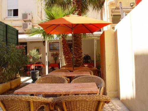 a table and chairs with an umbrella on a patio at Hôtel Belle Vue d'Angleterre in Le Grau-du-Roi