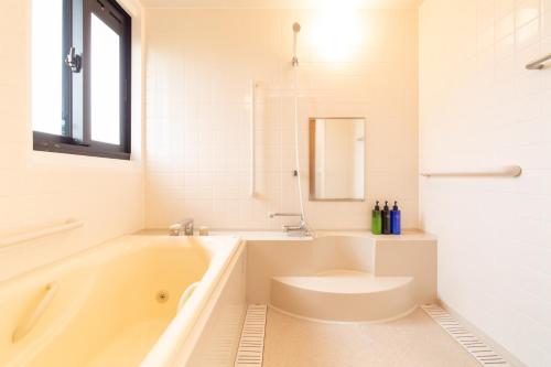 a white bathroom with a tub and a sink at Regina Ishigaki Kabira Sky / Two-Bedroom House in Kabira