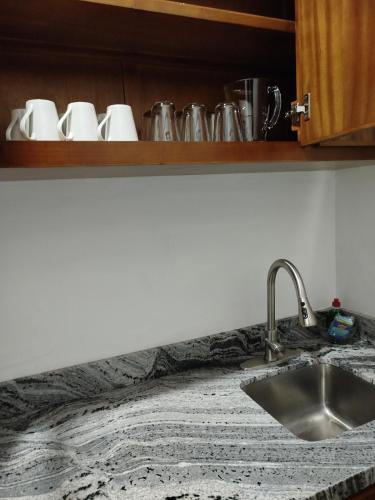 a kitchen counter top with a sink and cups on a shelf at Bungalows Anton in San Blas
