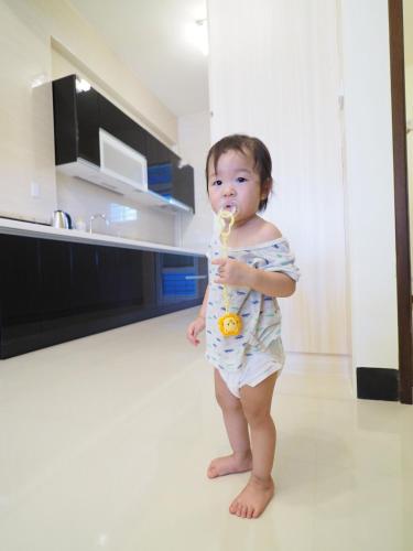 a baby standing in a kitchen with a toothbrush in its mouth at Love and Peace B&B in Taitung City