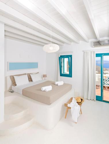 Un dormitorio blanco con una cama y un balcón. en Astypalaia Hotel Palace, en Astipalea