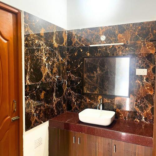 a bathroom with a sink and a black marble wall at Prysm Homestay - Kotagiri in Kotagiri