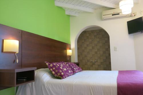 a bedroom with a white bed with a wooden headboard at E Luru in Mar de las Pampas