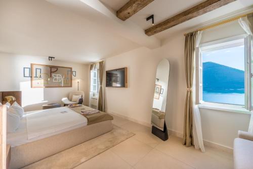 a bedroom with a large bed and a large window at Santa Boka Small Luxury Hotels of the World in Perast