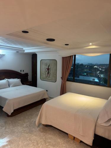 a bedroom with two beds and a large window at Hotel Americas Suites in Bogotá