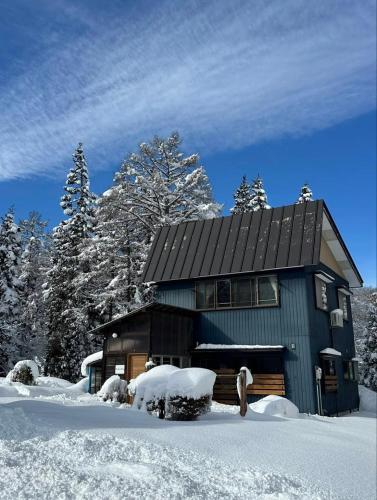 a house covered in snow with trees in the background at Karabiner House Myoko in Myoko