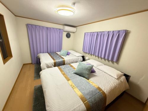 two beds in a room with purple curtains at HORIKIRI House TOKYO in Tokyo