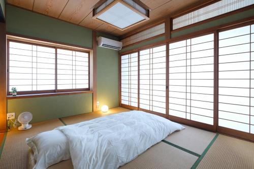 a bedroom with a bed in a room with windows at 空海の宿平生 in Saga