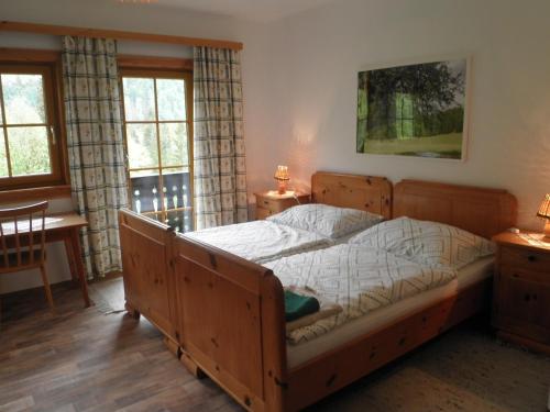 a bedroom with a wooden bed and a table and windows at Almurlaub Buchebnerreith, Ferienwohnungen in Hinterstoder