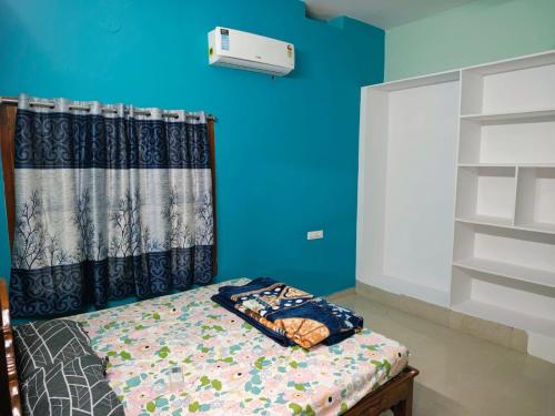 a bedroom with a bed and a blue wall at Elixir Mansion in Pālakollu