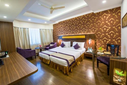 ein Hotelzimmer mit Bett, Tisch und Stühlen in der Unterkunft Swosti Grand Bhubaneswar in Bhubaneshwar