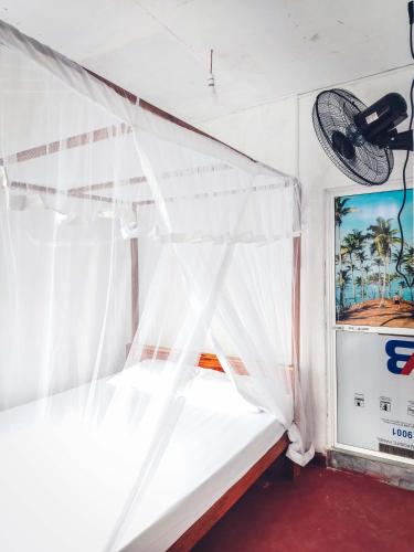 a bed with a canopy in a room with a window at Indrasiri Villa Midigama in Kumbalgama