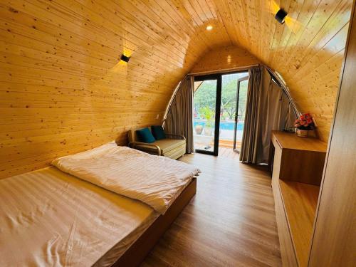 a bedroom with a bed in a wooden wall at Bình An Mountain Side Bungalow in Nguyên Ngoại