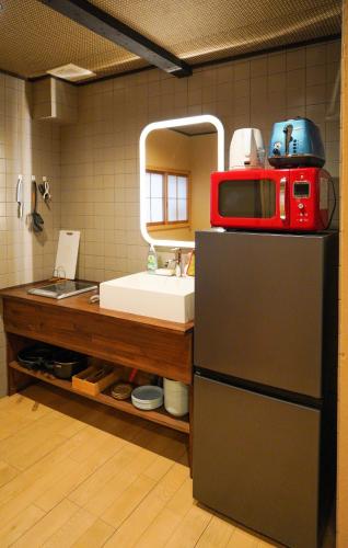a kitchen with a microwave on top of a refrigerator at Shirakabanoyado-DOUNIWA, Private House Near Osaka Castle, 白樺の宿-堂庭 in Osaka