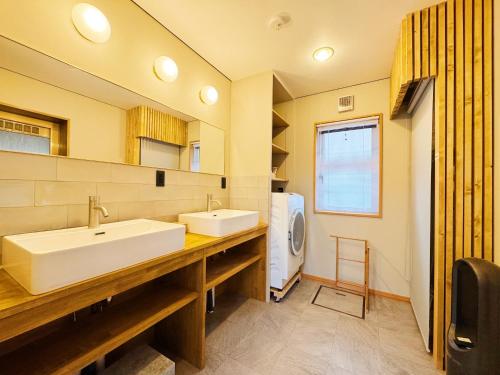 a bathroom with two sinks and a washer and dryer at Yunokawa Onsen KOMOREBISO in Hakodate
