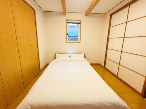 a large white bed in a room with a window at Yunokawa Onsen KOMOREBISO in Hakodate