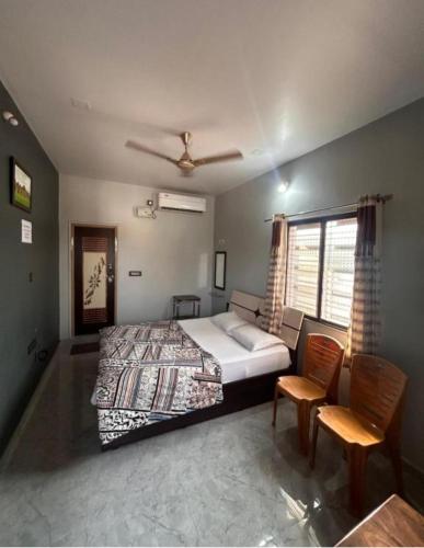 a bedroom with a bed and chairs and a window at Lee home stay in Hampi