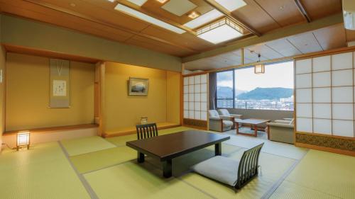 a living room with a table and chairs and a window at Tendo Onsen TAKINOYU in Tendo