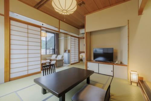a living room with a table and a tv at Tendo Onsen TAKINOYU in Tendo