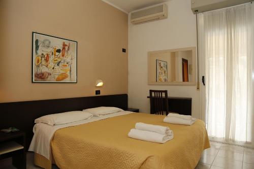 a bedroom with two beds with towels on them at Hotel Villa Dina in Rimini