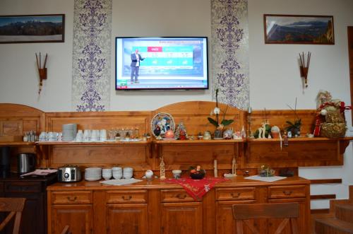 una TV sul muro sopra il bancone della cucina di Pensiunea Pasul Clabucetului a Predeal