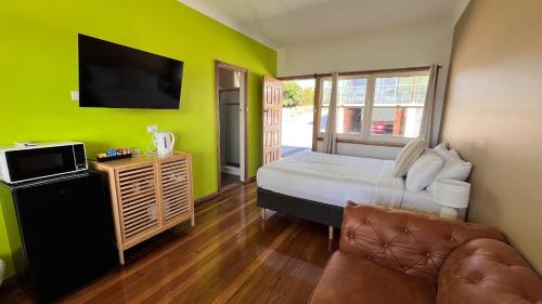 a bedroom with a bed and a tv and a couch at The Original Bel-Air Motel in Port Macquarie
