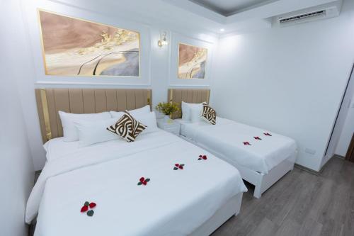 two beds in a room with white walls at Anna Noi Bai Airport Hotel in Sóc Sơn