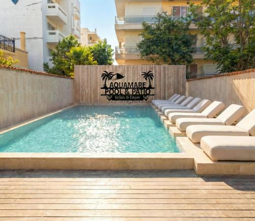 a swimming pool with lounge chairs in front of a building at AQUAMARE CITY and BEACH in Rhodes Town