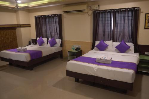 two beds in a hotel room with purple pillows at Hotel UR Comforts Jayanagar in Bangalore