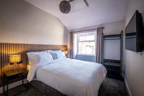 a bedroom with a large white bed and a window at Dalton Sq Apartments in Lancaster