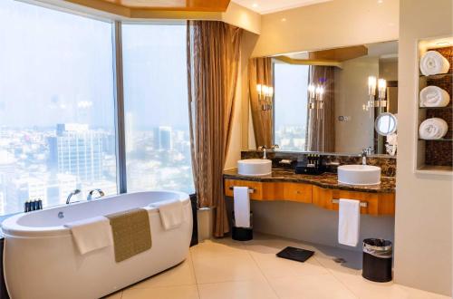 ein Badezimmer mit Badewanne, zwei Waschbecken und einem Fenster in der Unterkunft Lagos Continental Hotel in Lagos