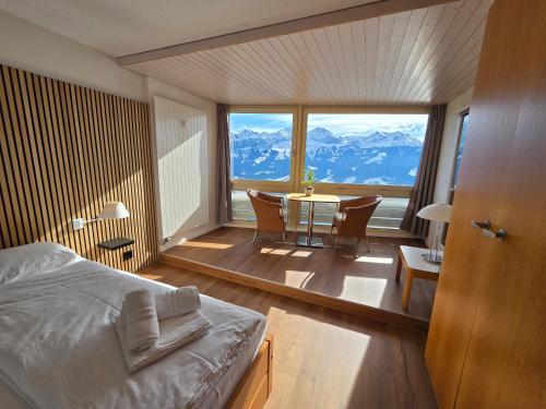 a bedroom with a bed and a table with a view at Alpine Luxury Suite Beatenberg in Beatenberg