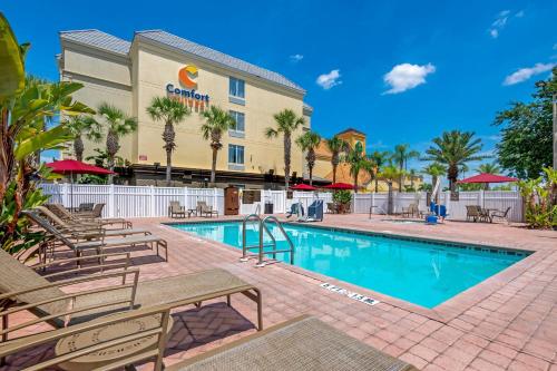 a pool at the resort with chairs and a hotel at Comfort Suites Near Universal Orlando Resort in Orlando