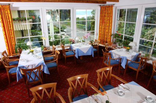 a restaurant with white tables and chairs and windows at Hotel Seeperle in Langenargen