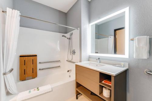 a bathroom with a sink and a tub and a mirror at Comfort Inn & Suites Weston - Wausau in Weston
