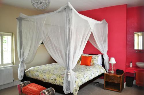 1 dormitorio con cama con dosel y pared roja en Bove Town House Apartments, en Glastonbury