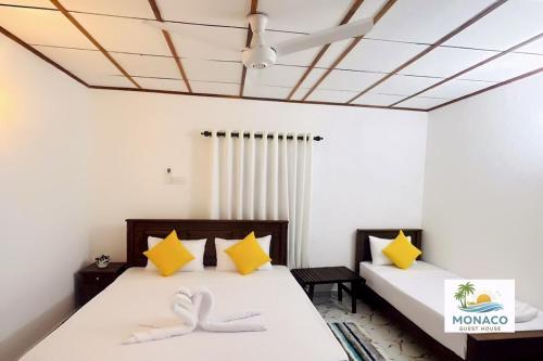 two beds in a room with yellow and white at Monaco Guest House in Devinuwara