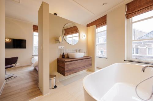a bathroom with a tub and a sink and a mirror at Boutique Hotel Jeroen in Den Bosch