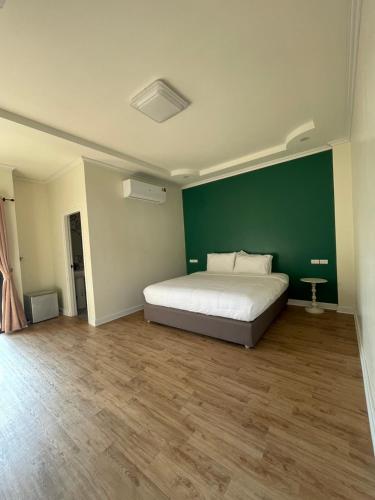 a bedroom with a bed and a green wall at Natcha Hotel and Residence in Sathani Chumphon