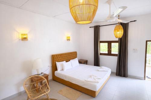 a bedroom with a bed and a chair and a window at The Jungle Pearl Hotel in Udawalawe