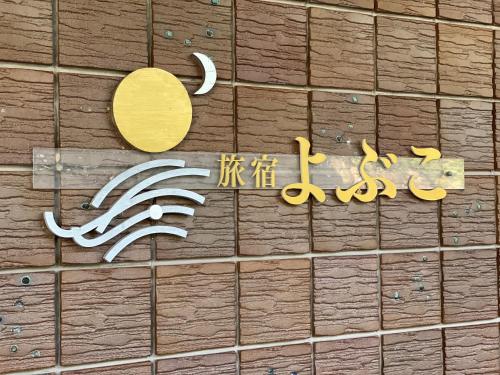 a sign on a tiled wall with writing on it at Tabiyado Yobuko in Karatsu