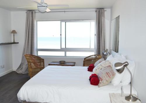 a bedroom with a white bed with a large window at Blouberg Studio Wow in Bloubergstrand