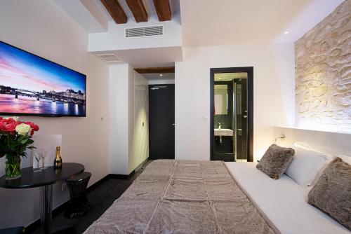 a bedroom with a white bed and a table with flowers at Hôtel le Clos de Notre Dame in Paris