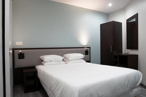 a bedroom with a large bed with white sheets and pillows at Aero Hotel in Issy-les-Moulineaux