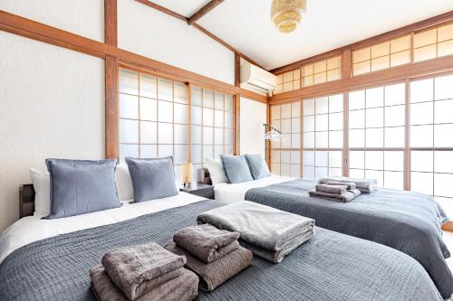 two beds in a room with large windows at Comfort Villa Takahata in Takahate